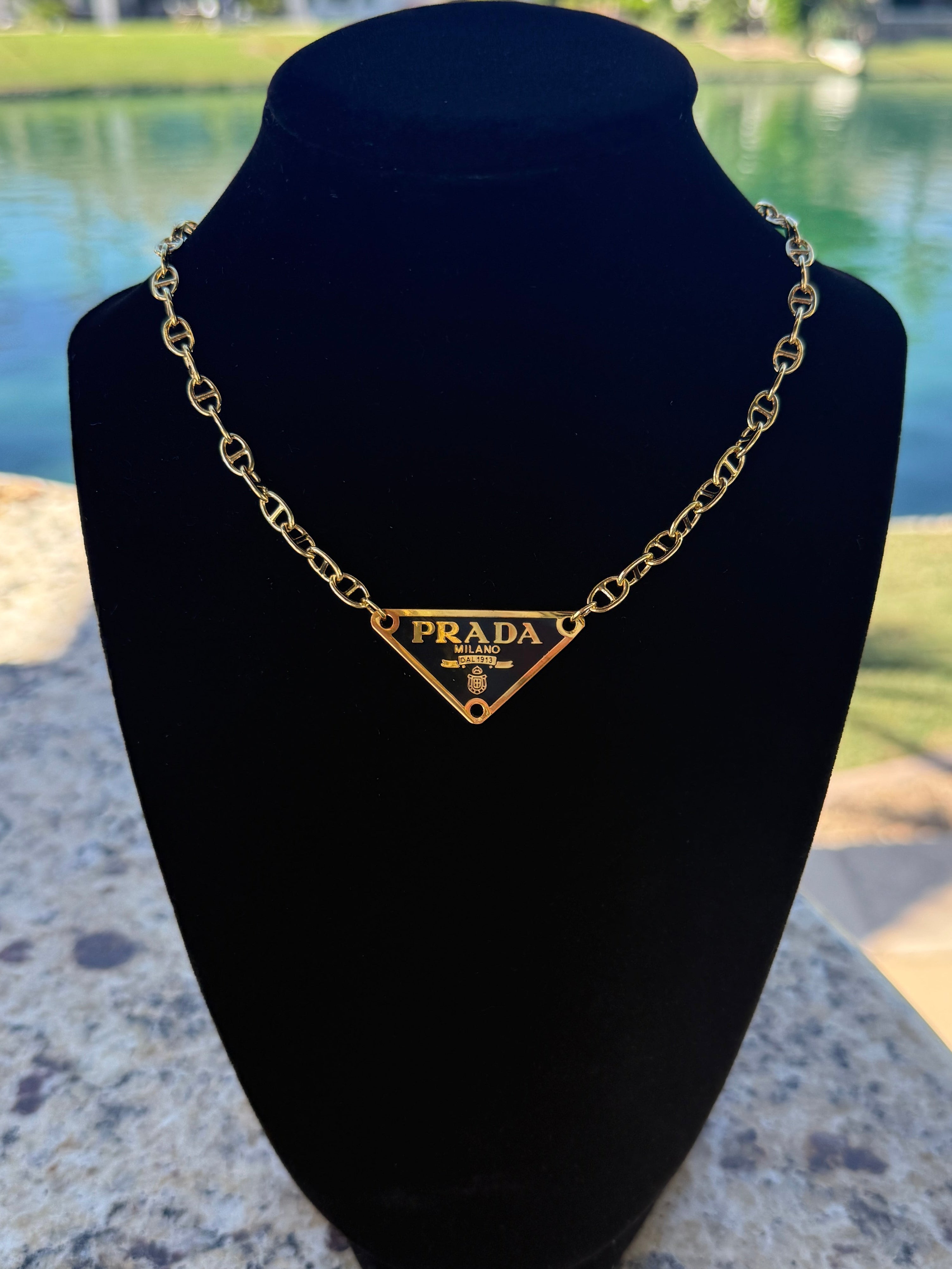 Prada necklace on a black velvet stand with a scenic background